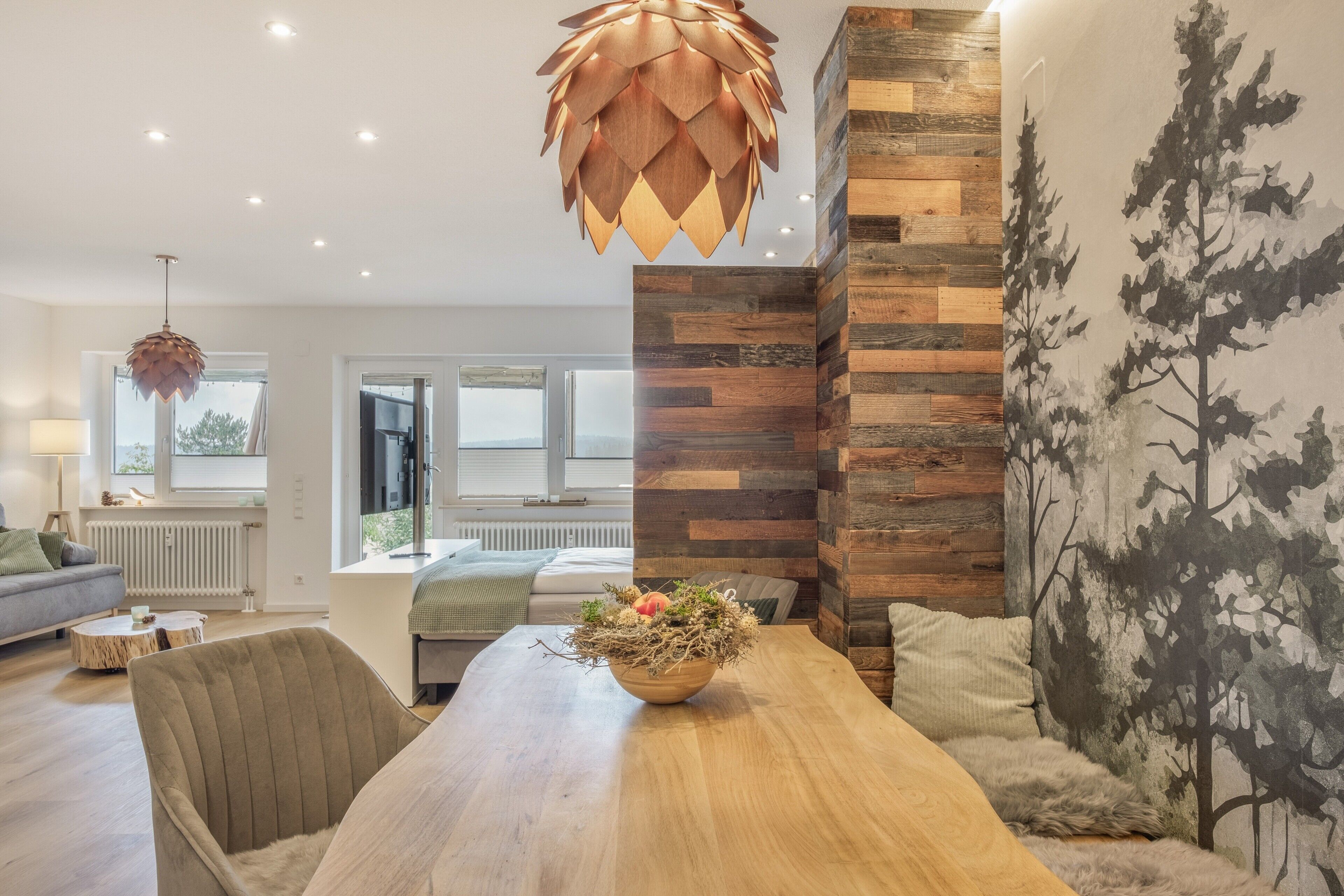 A modern living room with a wooden dining table, a sofa, and a large window.
