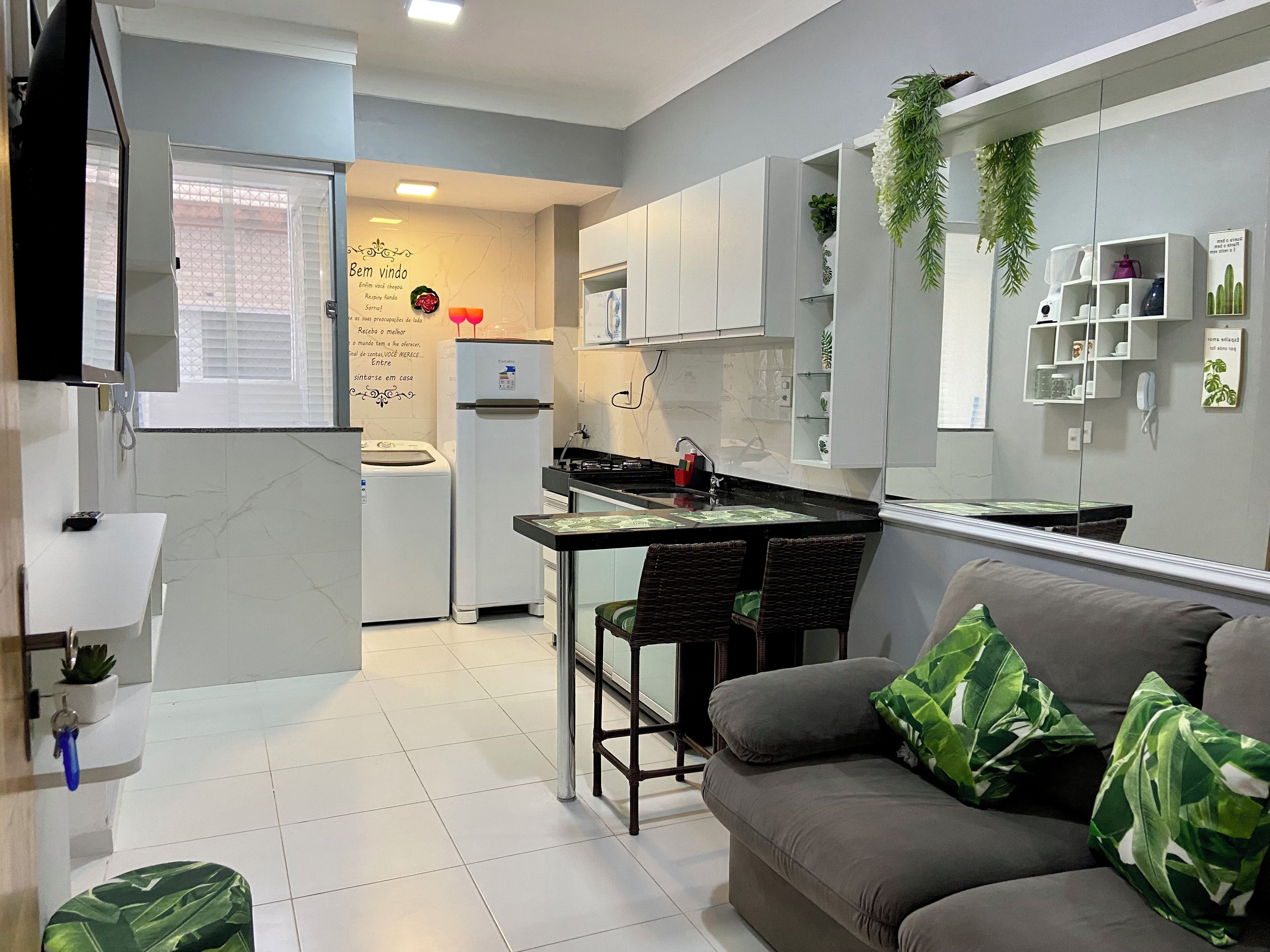Una cocina moderna con armarios blancos, un refrigerador y una zona de comedor con un taburete de bar.