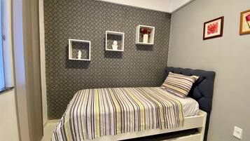 Un dormitorio con una cama, una pared con diseños hexagonales y tres cuadros enmarcados.