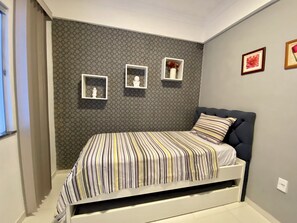 Une chambre à coucher avec un lit, un mur orné de motifs hexagonaux et trois tableaux encadrés.
