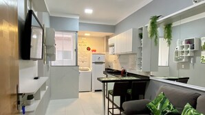 Una cocina moderna con armarios blancos, un comedor con mesa y sillas, y un ventilador de techo.