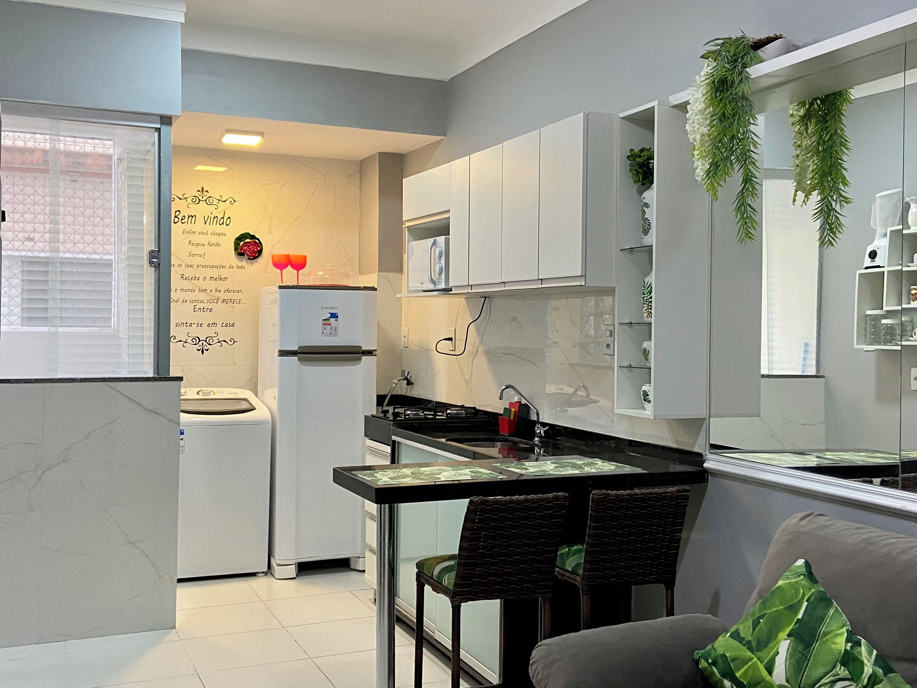 A modern kitchen with white cabinets, a refrigerator, a microwave, and a dining area with a table and chairs.