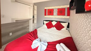 Una habitación de hotel con cama, armario, estante con objetos decorativos y pared con textura.