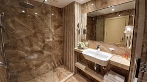 Un baño moderno con ducha envuelta en vidrio, tocador con lavabo y espejo.