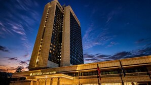 Un edificio de hotel moderno con una entrada destacada y señalización para el Astoria Grand Hotel.