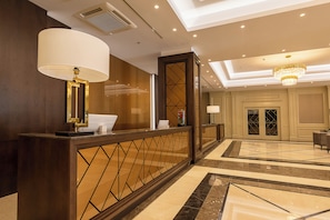 Een hotellobby met een receptiebalie, een kroonluchter en een incheckbalie.