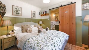 A neatly made bed with a floral bedspread, a bedside lamp, and a nightstand with a lamp.