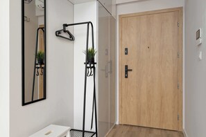 A bathroom with a mirror, a towel rack, a shower, and a wooden door. - Funkcjonalne Studio z Klimatyzacja i Miejscem do Pracy by Noclegi Renters (Katowice)
