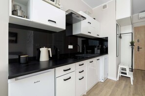 A modern kitchen with white cabinetry, black countertops, and a built-in oven. - Funkcjonalne Studio z Klimatyzacja i Miejscem do Pracy by Noclegi Renters (Katowice)