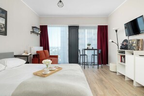 Una habitación de hotel con cama, escritorio, silla, televisor y estantería.