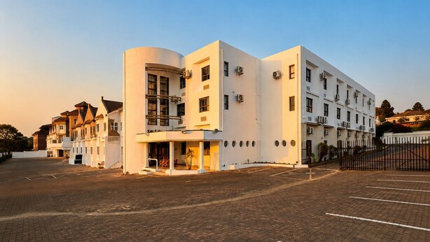 A multi-story hotel with a modern design, featuring a central courtyard and a parking area.