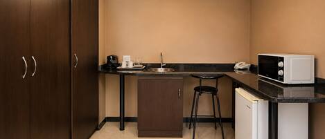 A compact kitchen with a sink, a microwave, and a coffee maker.