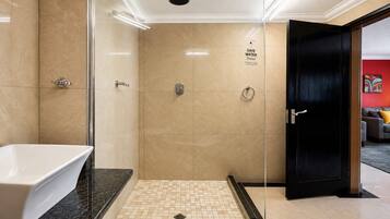 A modern bathroom with a glass-enclosed shower, a white sink, and a tiled floor.