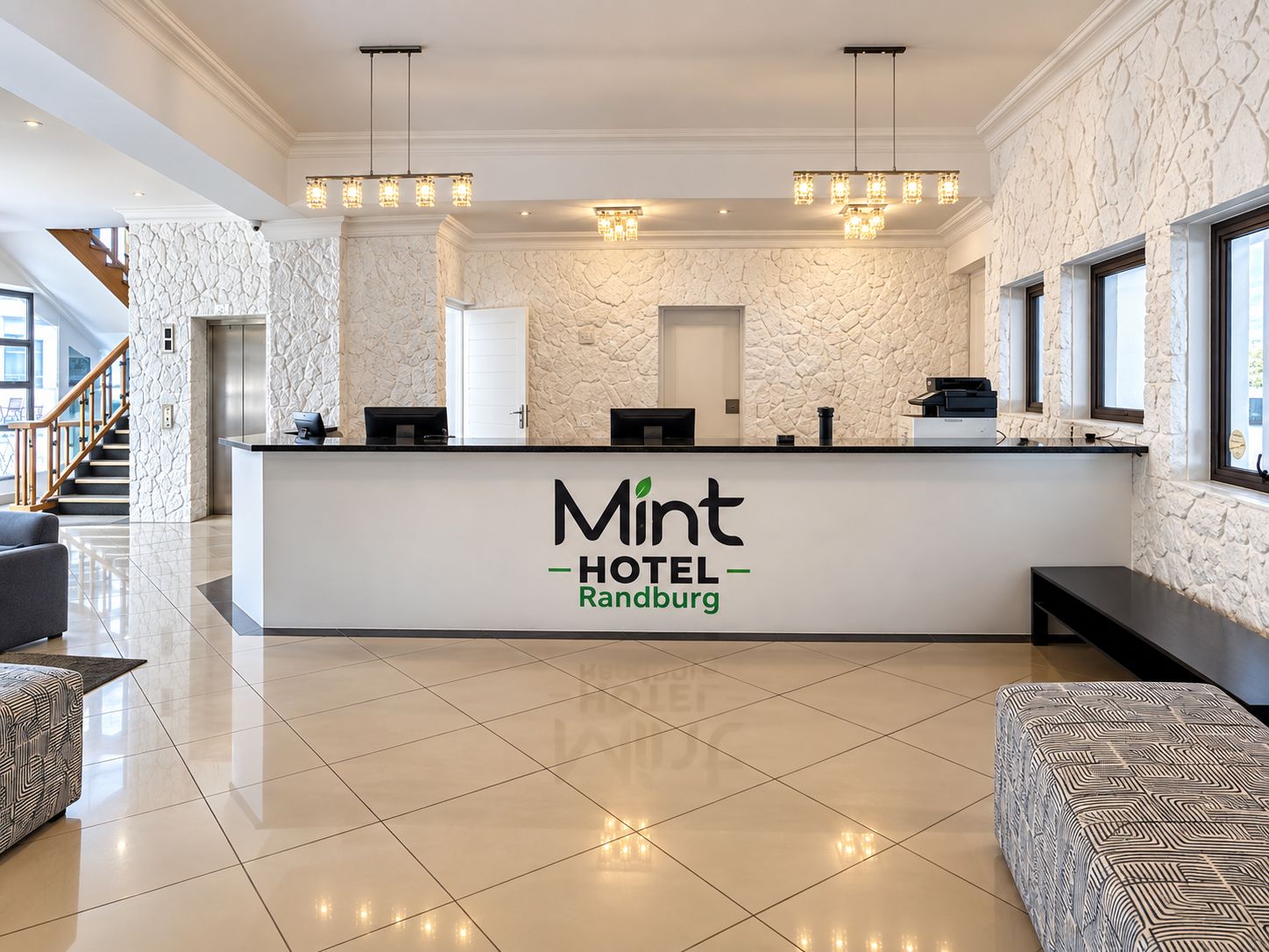 Zona de recepción de un hotel con diseño moderno, que incluye un mostrador, una escalera y un área de estar.