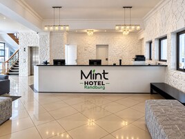 Un'area di ricevimento di un hotel dal design moderno, con una reception, una scala e una zona relax.