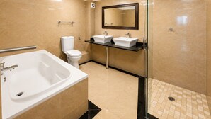 A modern bathroom with a bathtub, toilet, and two sinks.
