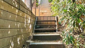 A wooden staircase leading up to a house with a wooden fence on one side and dense foliage on the other. - One-bedroom apartment in Rupione with exceptional ocean views, a 6-minute walk from the beach (Pietrosella)