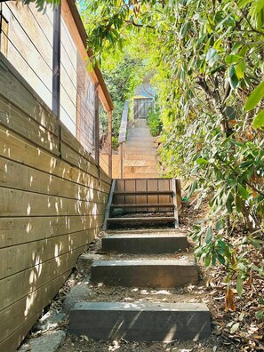 A wooden staircase leading up to a house with a wooden fence on one side and dense foliage on the other. - One-bedroom apartment in Rupione with exceptional ocean views, a 6-minute walk from the beach (Pietrosella)
