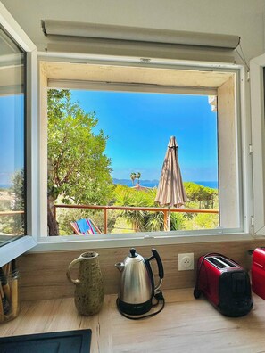 A kitchen with a view of a balcony, a kettle, a toaster, and a table. - One-bedroom apartment in Rupione with exceptional ocean views, a 6-minute walk from the beach (Pietrosella)