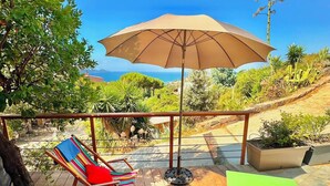 A wooden deck with outdoor seating, including a table and chairs, and a large umbrella providing shade. - One-bedroom apartment in Rupione with exceptional ocean views, a 6-minute walk from the beach (Pietrosella)