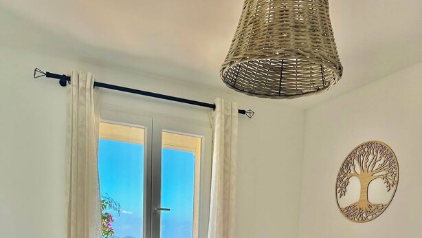 A bedroom with a bed, a bedside table with a lamp, a mirror, and a view of the sea through a window. - One-bedroom apartment in Rupione with exceptional ocean views, a 6-minute walk from the beach (Pietrosella)