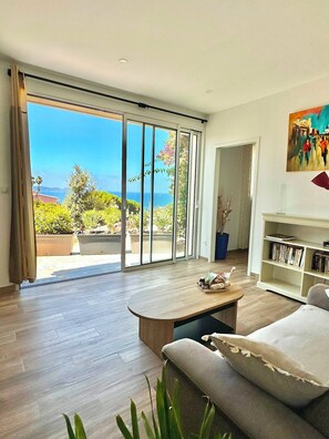 A spacious living room with a large sliding glass door leading to a balcony, a wooden coffee table, a sofa, and a bookshelf. - One-bedroom apartment in Rupione with exceptional ocean views, a 6-minute walk from the beach (Pietrosella)