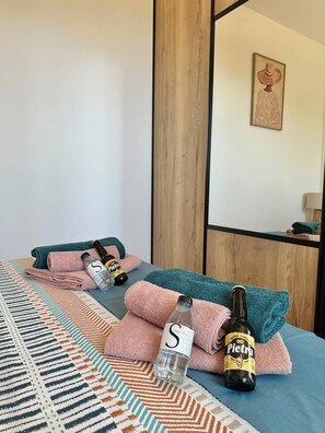 A hotel room with a bed, towels, a bottle of beer, and a glass. - One-bedroom apartment in Rupione with exceptional ocean views, a 6-minute walk from the beach (Pietrosella)