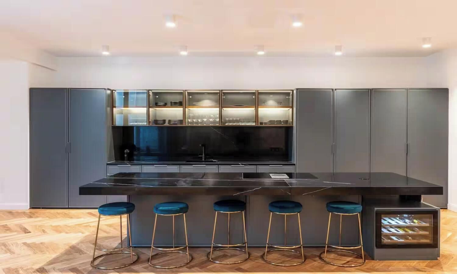 Una cocina moderna con una isla central, taburetes de bar y armarios empotrados.