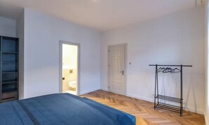 Un dormitori amb un llit, un armari, una porta i un escorredor metàl·lic.