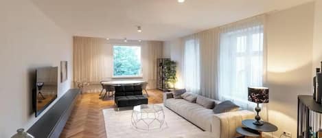 Una sala de estar moderna con sofá, reposapiés, mesa de centro y televisión montada en la pared.