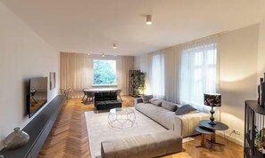 A modern living room with a sofa, ottoman, coffee table, and a TV mounted on the wall. - IDEALLY LOCATED NEAR THE VIBRANT AND ICONIC HACKESCHER MARKT -  150 SQM (Berlin)
