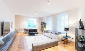 Ein modernes Wohnzimmer mit Sofa, Couchtisch, Fernseher und einem Essbereich mit Tisch und Stühlen.