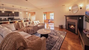 A modern living room with a fireplace, a sofa set, a coffee table, and a kitchen in the background. - Weekend Vibes - 1 Level - Pool - Hot Tub - Fenced Yard (Sevierville)
