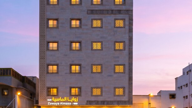 A modern building with a flat facade, multiple windows, and a visible entrance. - Zawaya Almasiya Alawali Apartments (Madinah)