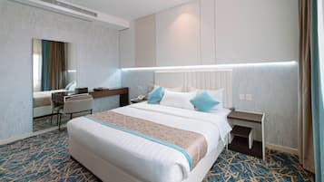 Una habitación de hotel con una cama grande, mesitas de noche, un escritorio y un espejo.