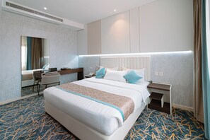 A hotel room with a large bed, bedside tables, a desk, and a mirror. - Zawaya Almasiya Alawali Apartments (Madinah)