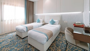 A hotel room with two beds, a desk, a telephone, and a minibar. - Zawaya Almasiya Alawali Apartments (Madinah)