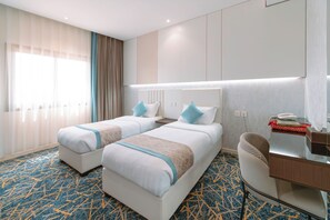 Et hotelværelse med to senge, et skrivebord, en telefon og et minibar.