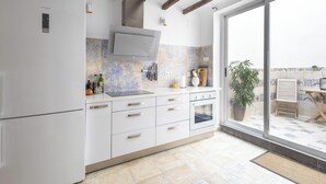 Una cocina moderna con armarios blancos, horno integrado y un amplio ventanal con vistas a un patio.