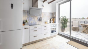 A modern kitchen with white cabinets, a built-in oven, and a large window overlooking a patio area.