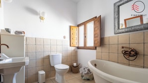 Een badkamer met een wastafel, toilet, badkuip en een raam met houten luiken.