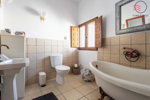 A bathroom with a sink, toilet, bathtub, and a window with wooden shutters. - CASA AZUL (Finestrat)