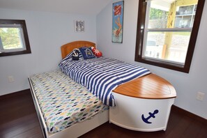 A bedroom with a bed featuring a striped blanket and a boat-shaped headboard. - Relax at Our Lake House Cottage-Heart of Osage Beach-One of a Kind (Osage Beach)