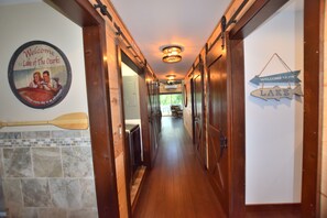 A wooden hallway with a welcome sign for Lake of the Ozarks, a paddle, and a fish-shaped welcome sign. - Relax at Our Lake House Cottage-Heart of Osage Beach-One of a Kind (Osage Beach)