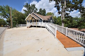 A two-story house with a wooden deck and white railings. - Relax at Our Lake House Cottage-Heart of Osage Beach-One of a Kind (Osage Beach)