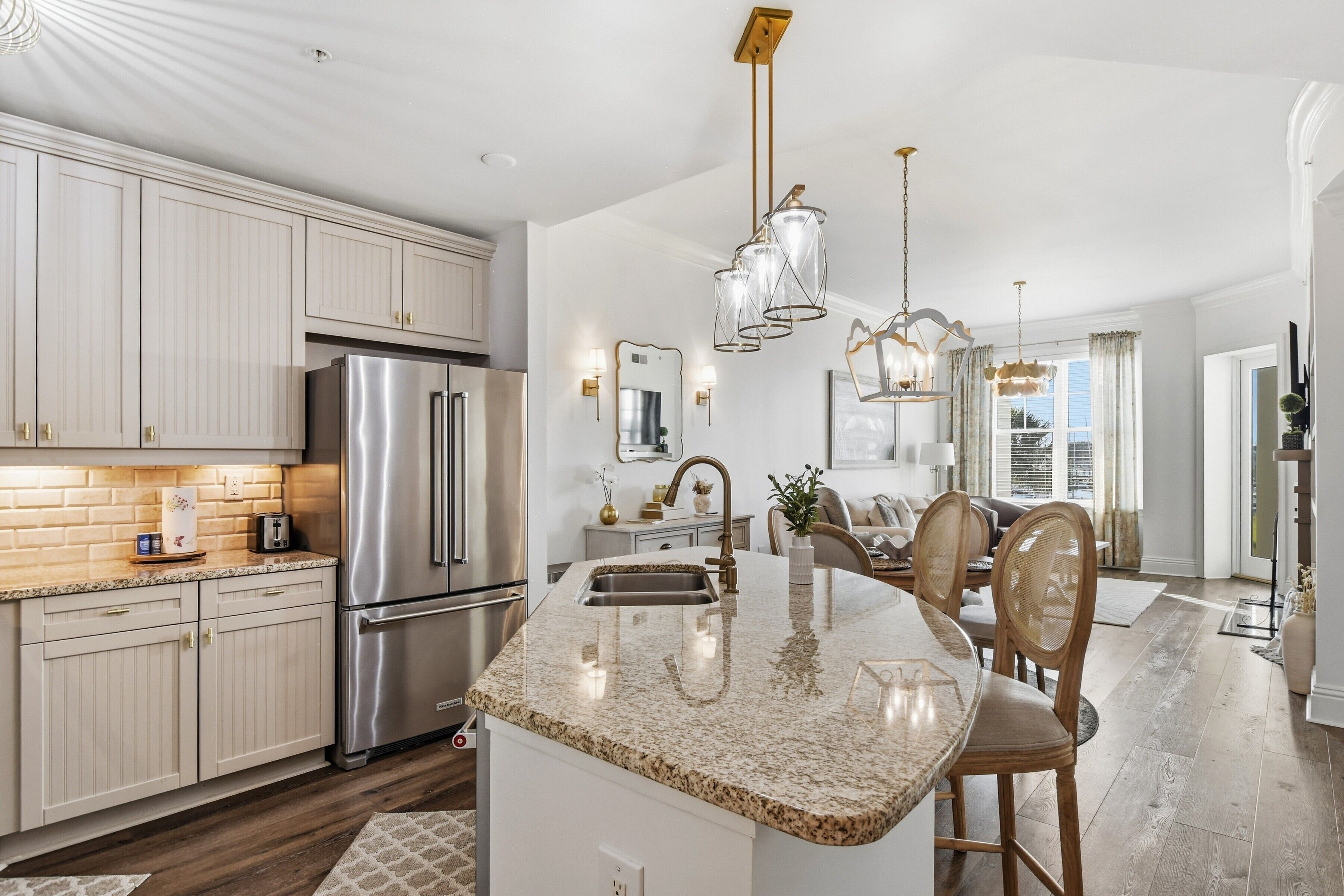 A modern kitchen with stainless steel appliances, a granite countertop, and a dining area with wooden chairs.