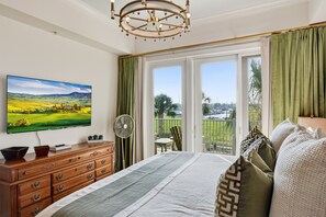 Ein Schlafzimmer mit einem großen Bett, einem Fernseher, einem Schminktisch und einem Balkon mit Blick.