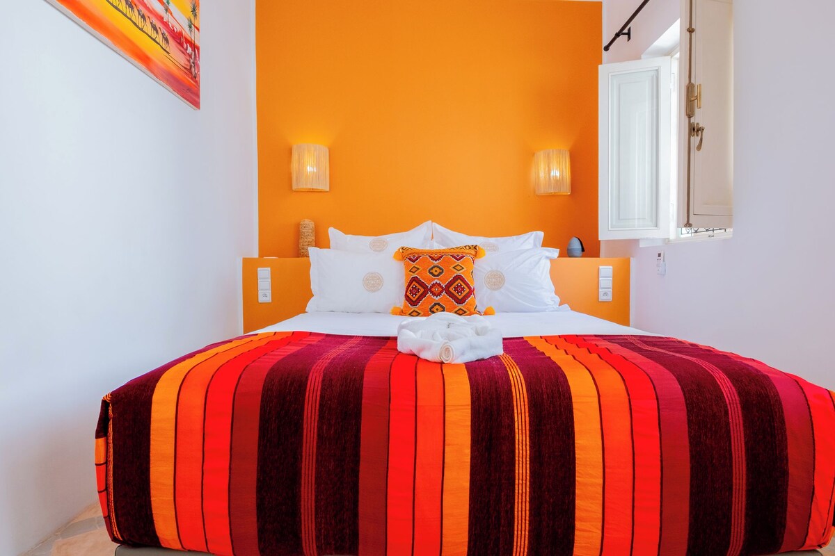 A bed with a striped blanket, white pillows, and a decorative pillow.