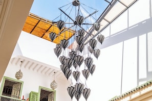 A chandelier with multiple hanging lights in a spacious interior. - Riad Thaïs (Marrakech)
