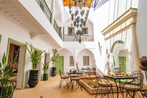 A spacious courtyard with a dining area, potted plants, and a view of the surrounding architecture. - Riad Thaïs (Marrakech)